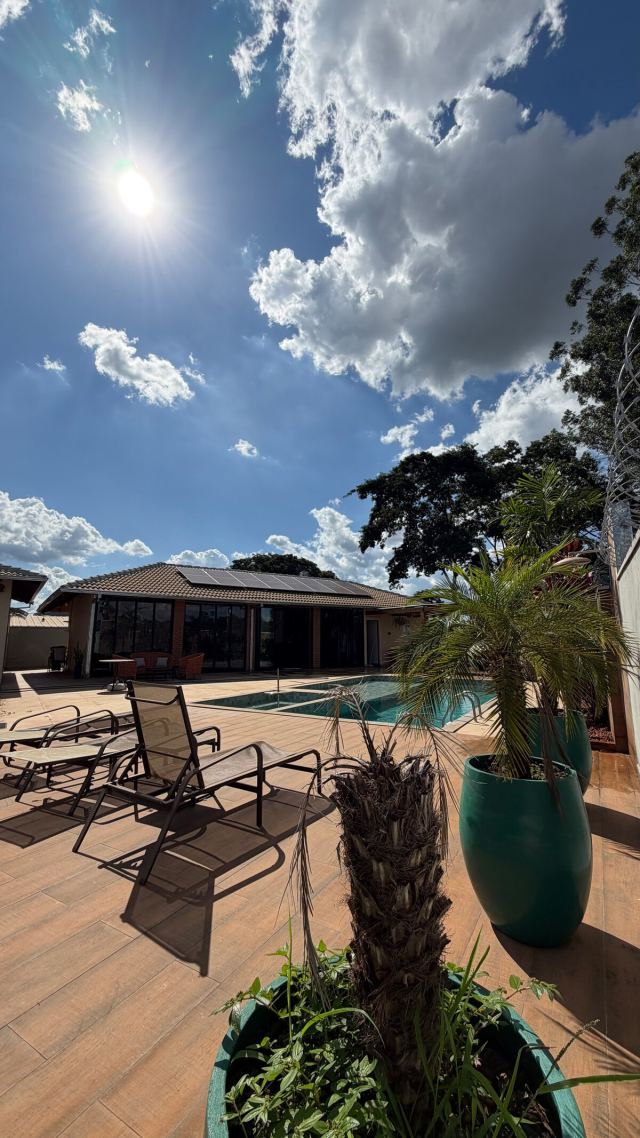 Espreguiçadeiras no deck da piscina, com o salão coberto ao fundo