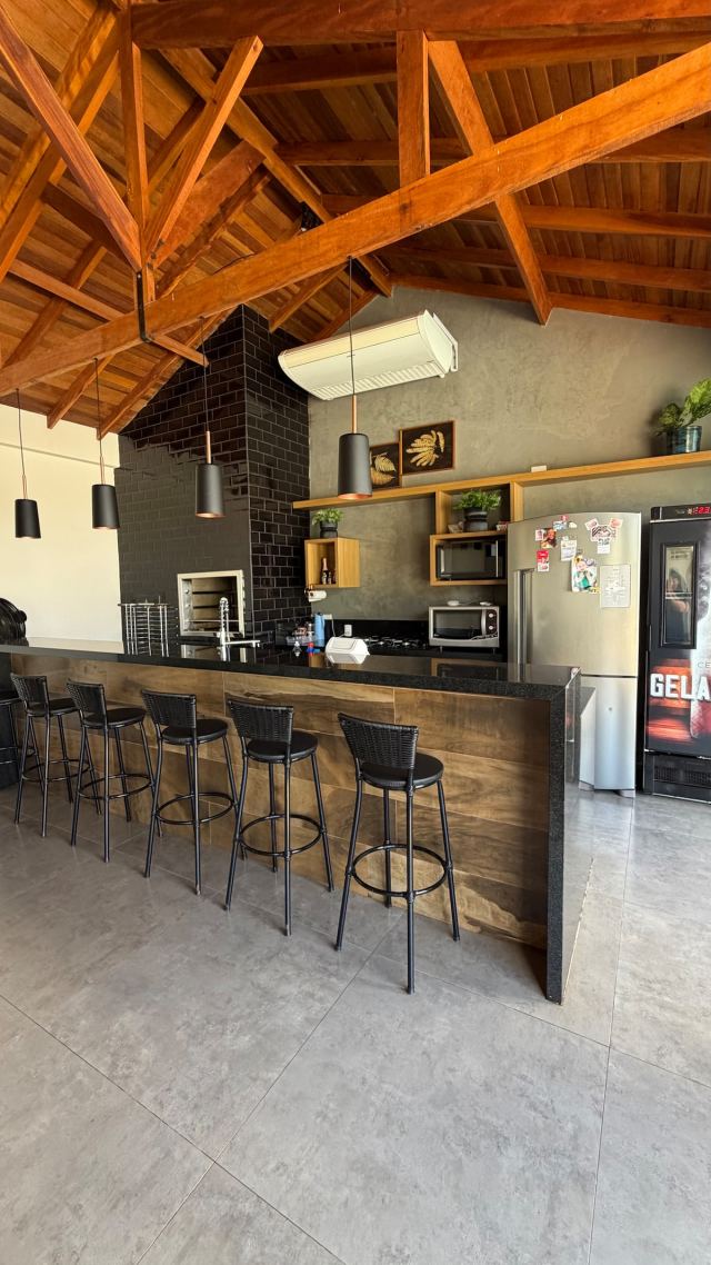 Área gourmet com bancada, banquetas e geladeira de bebidas
