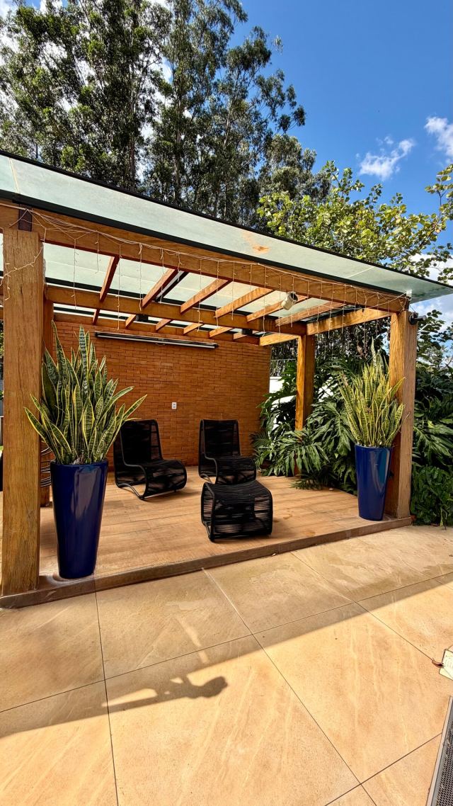 Pergolado com poltronas e plantas ao lado do deck